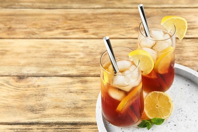 Photo of Glasses of refreshing iced tea on wooden table. Space for text