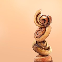 Cinnamon rolls balancing on peach color background, space for text