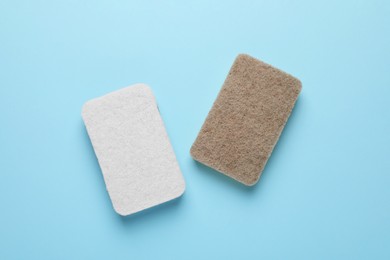 Photo of New sponges on light blue background, flat lay