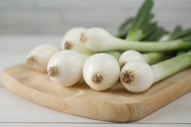 Photo of Fresh green spring onions on white wooden table, closeup.