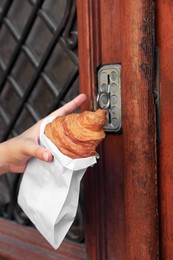 Photo of Woman with croissant opening door, closeup view