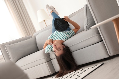 Photo of Woman with hand fan suffering from heat at home. Summer season