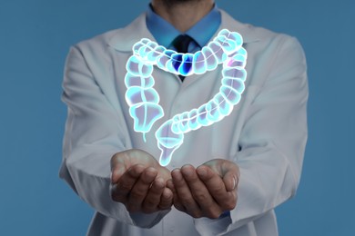 Gastroenterologist holding illustration of large intestine on light blue background, closeup