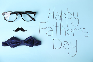Flat lay composition with bow tie and eyeglasses on  light blue background. HAPPY FATHER'S DAY greeting card