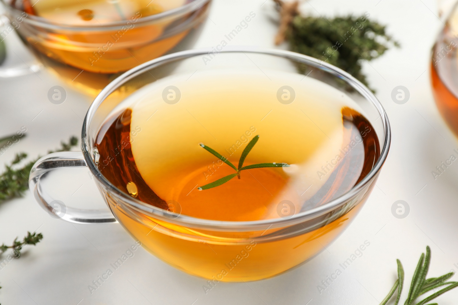 Photo of Aromatic herbal tea with thyme and rosemary on white marble table, closeup