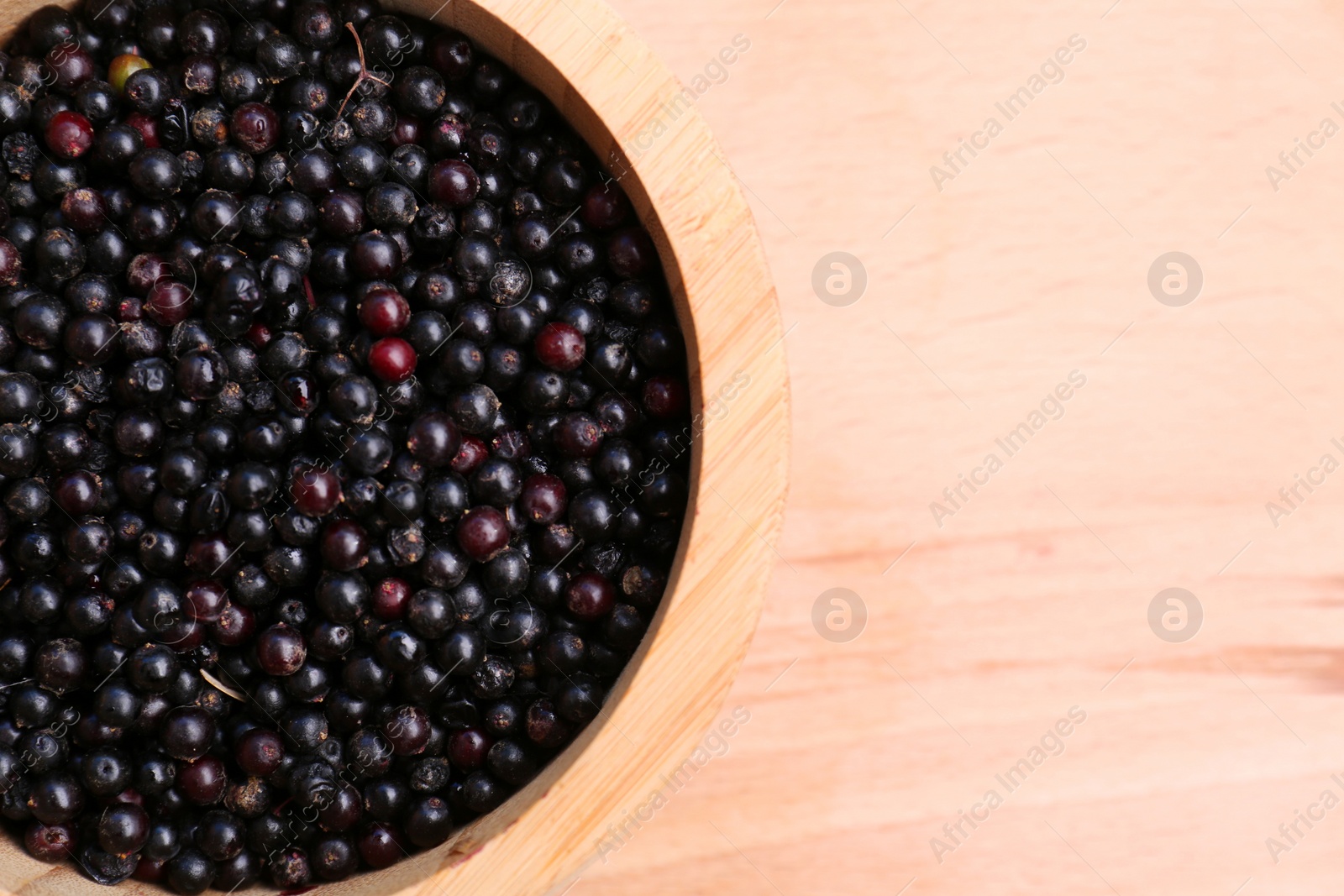 Photo of Tasty elderberries (Sambucus) on wooden table, top view. Space for text
