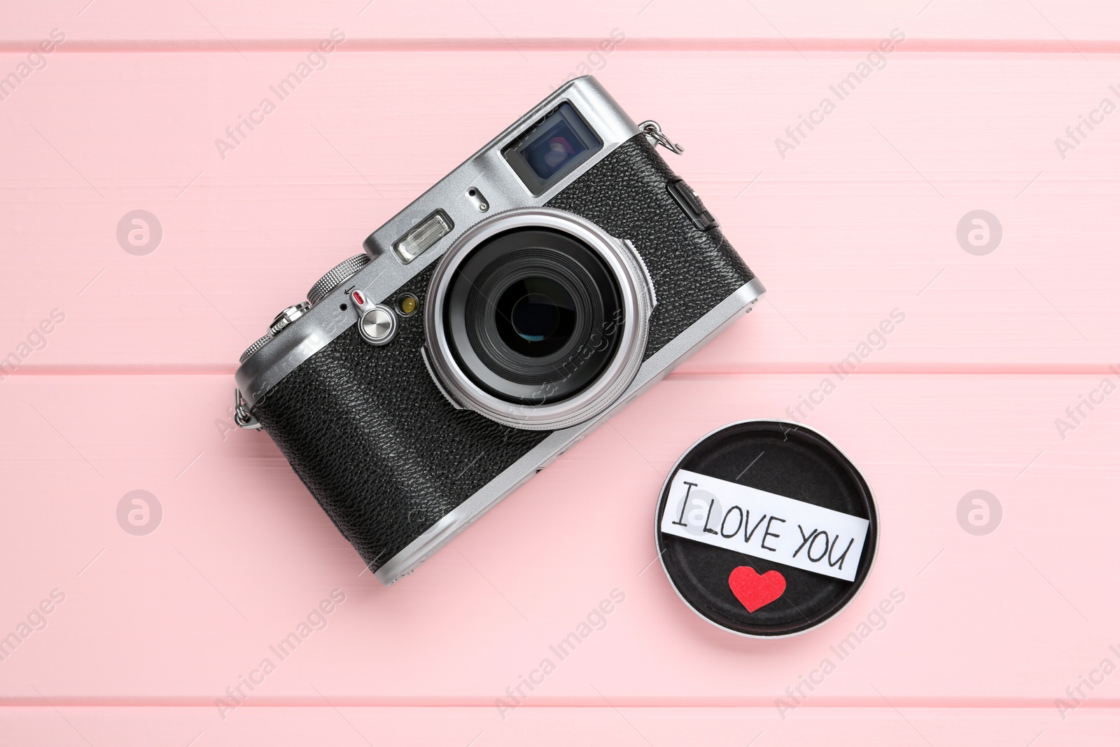 Photo of Vintage camera and body cap with phrase I Love You on pink wooden background, flat lay