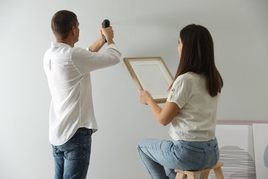Photo of Couple decorating room with picture together. Interior design
