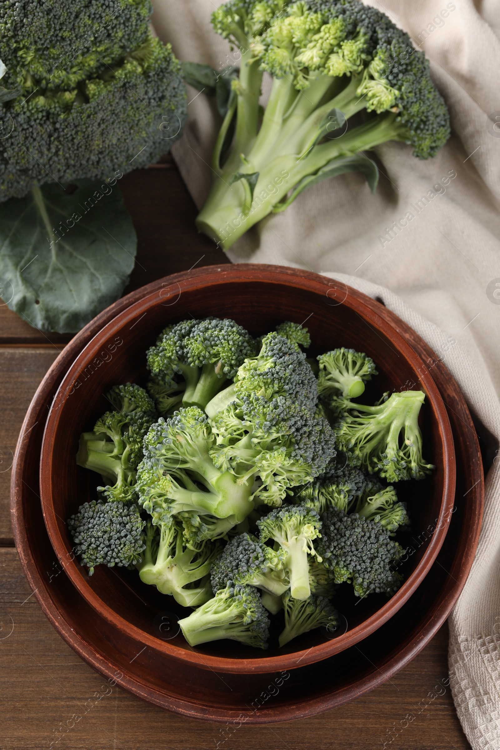 Photo of Bowl with fresh raw broccoli on wooden table, flat lay