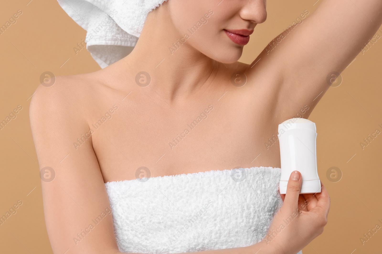 Photo of Woman applying deodorant on beige background, closeup