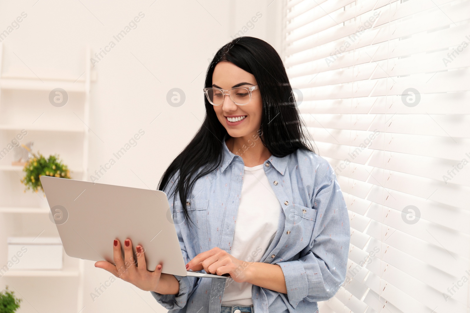 Photo of Beautiful young woman working with laptop indoors