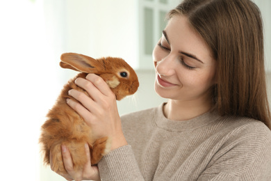 Young woman with adorable rabbit indoors. Lovely pet