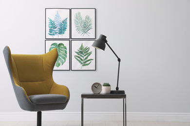 Photo of Stylish room interior with comfortable armchair and paintings of tropical leaves