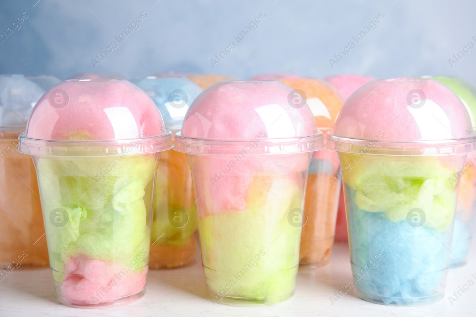 Photo of Many plastic cups with tasty cotton candies on white wooden table