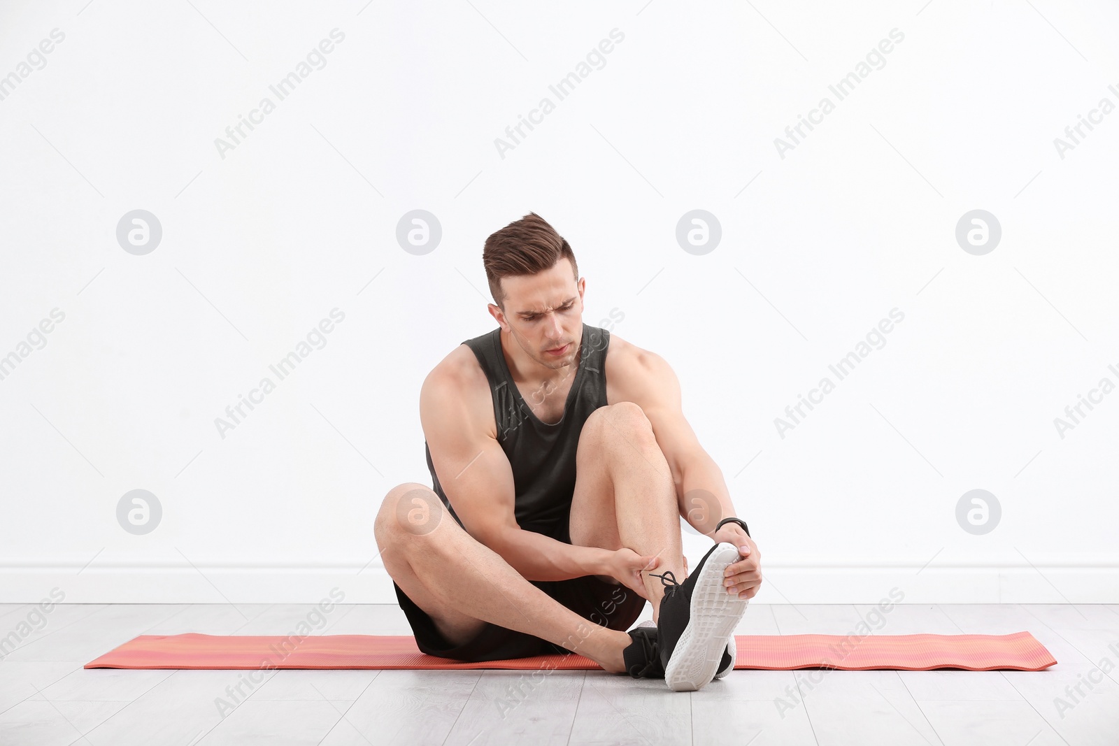 Photo of Male athlete suffering from leg pain during training indoors