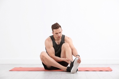 Photo of Male athlete suffering from leg pain during training indoors