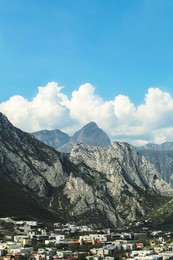 City near mountains under blue sky with clouds