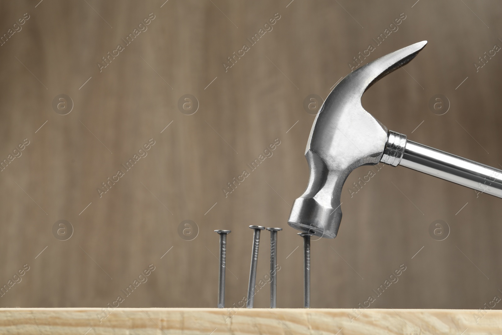 Photo of Hammering nail into plank against wooden background, space for text