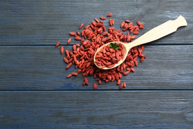 Photo of Spoon and dried goji berries on blue wooden table, top view with space for text. Healthy superfood