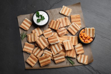 Delicious pita chips and sauce on black table, top view