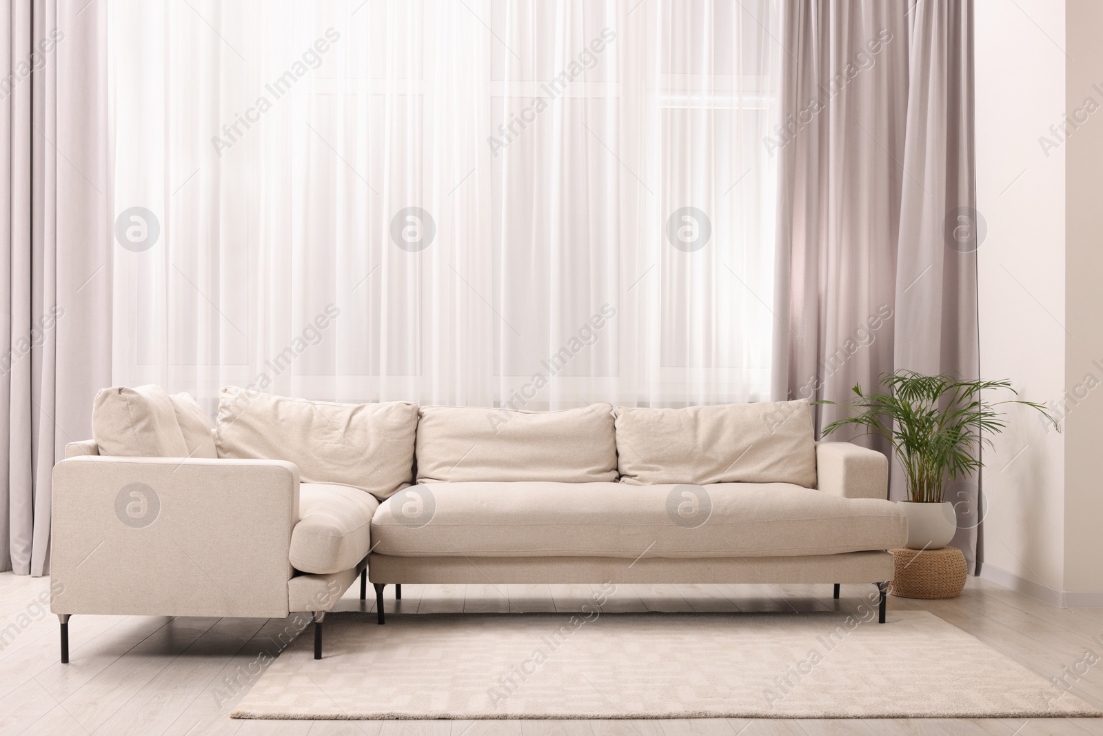 Photo of Comfortable sofa and window with beautiful curtains in room. Interior design