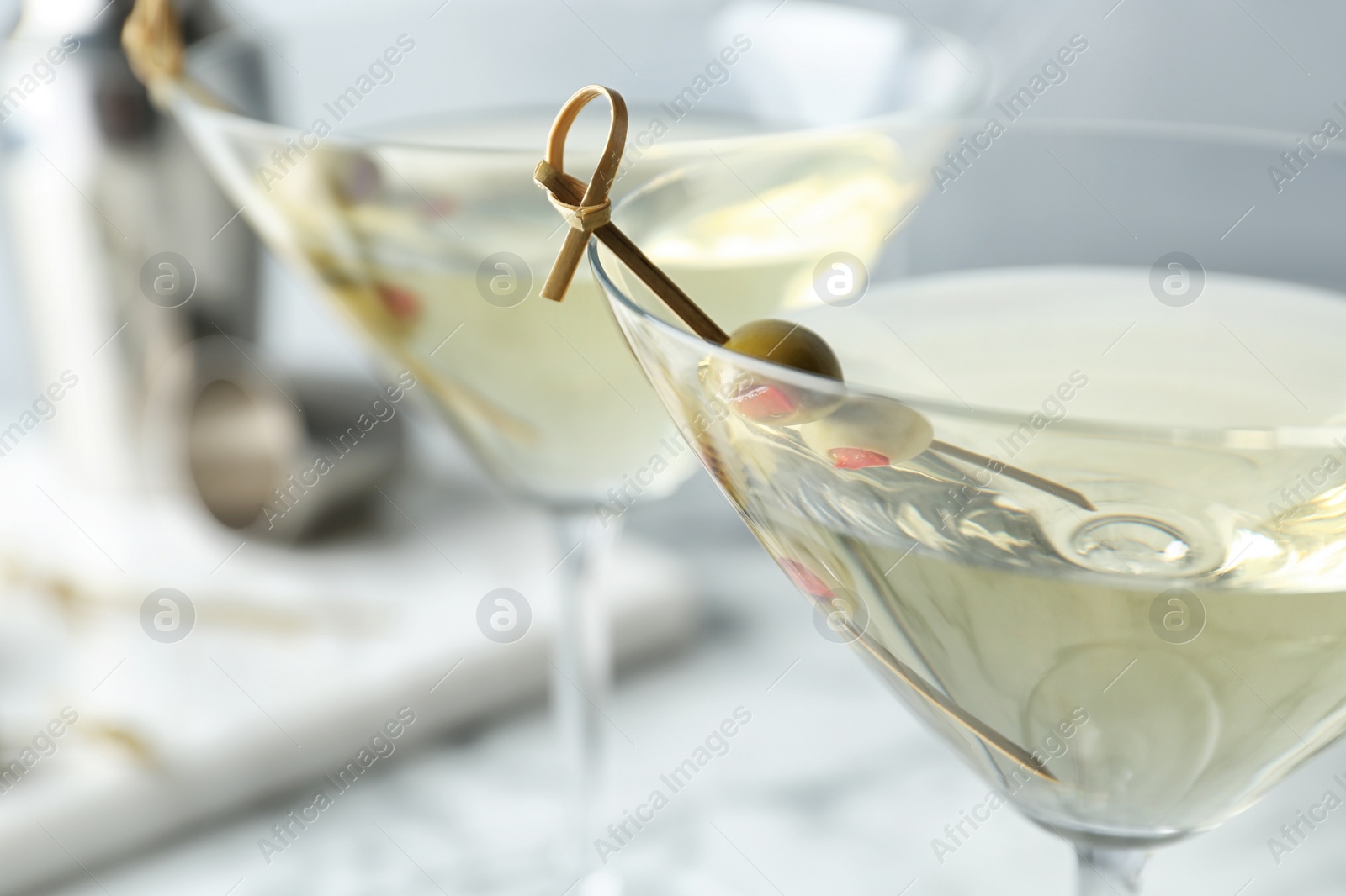 Photo of Glasses of Classic Dry Martini with olives on table, closeup