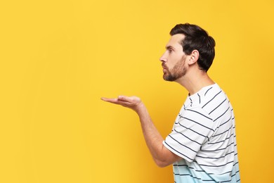 Handsome man blowing kiss on orange background. Space for text