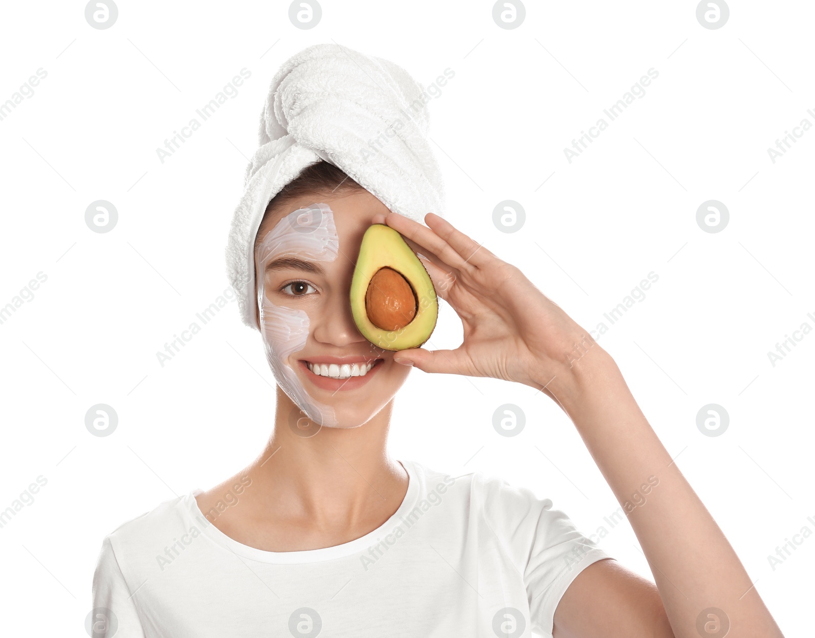 Photo of Happy young woman with organic mask on her face holding avocado against white background