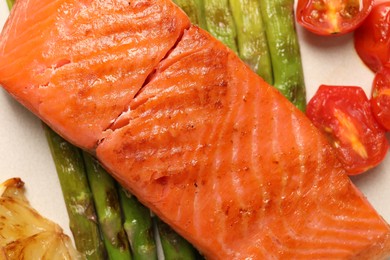 Photo of Tasty grilled salmon with asparagus, tomatoes and lemon on plate, flat lay