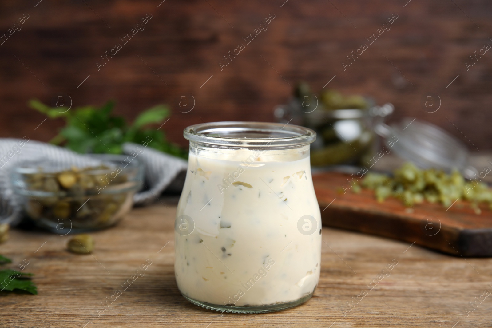 Photo of Tasty tartar sauce in glass jar on wooden table