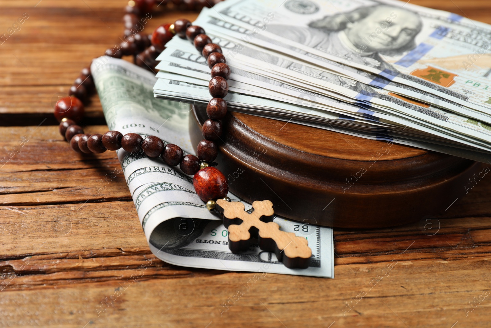 Photo of Cross and money on wooden table, closeup