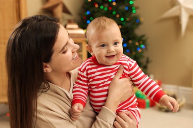 Photo of Happy you mother with her cute baby in room decorated for Christmas. Winter holiday