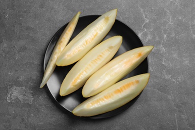 Photo of Slices of delicious honey melon on black table, top view