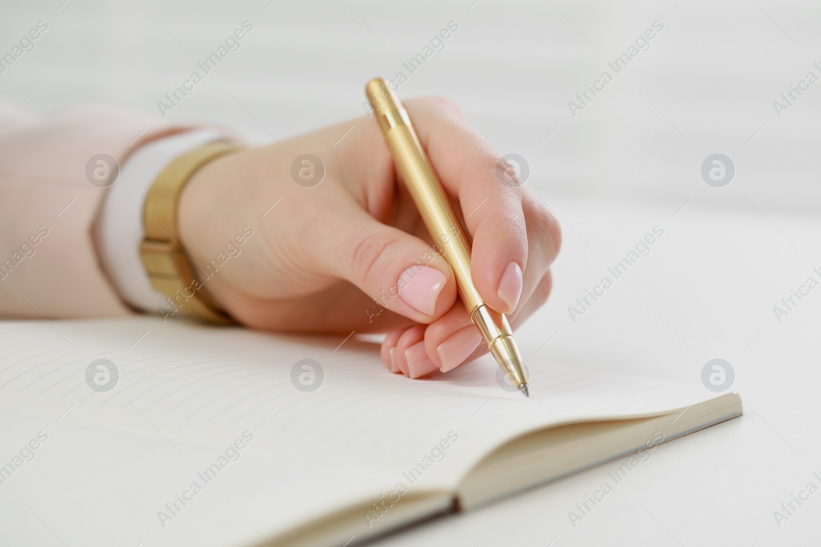 Photo of Woman writing in notebook at white table, closeup