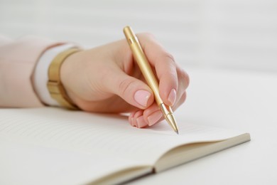 Photo of Woman writing in notebook at white table, closeup