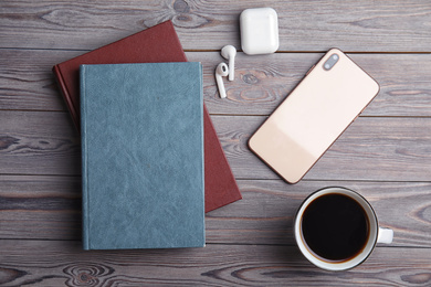 Books, coffee, earphones and mobile phone on light grey wooden table, flat lay