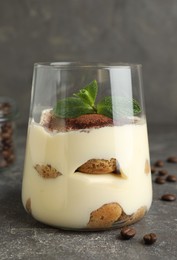 Photo of Delicious tiramisu with mint in glass on grey table