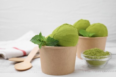 Photo of Paper cups with tasty matcha ice cream on white wooden table, closeup