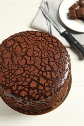 Photo of Delicious chocolate truffle cake and knife on light wooden table, above view