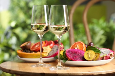 Delicious exotic fruits and wine on wooden table