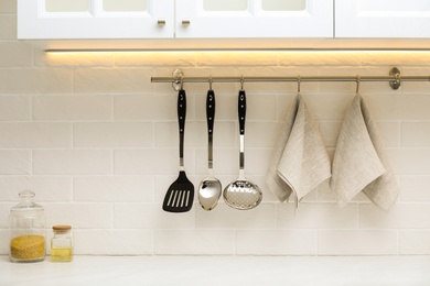 Photo of Kitchen utensils and clean towels hanging on wall indoors