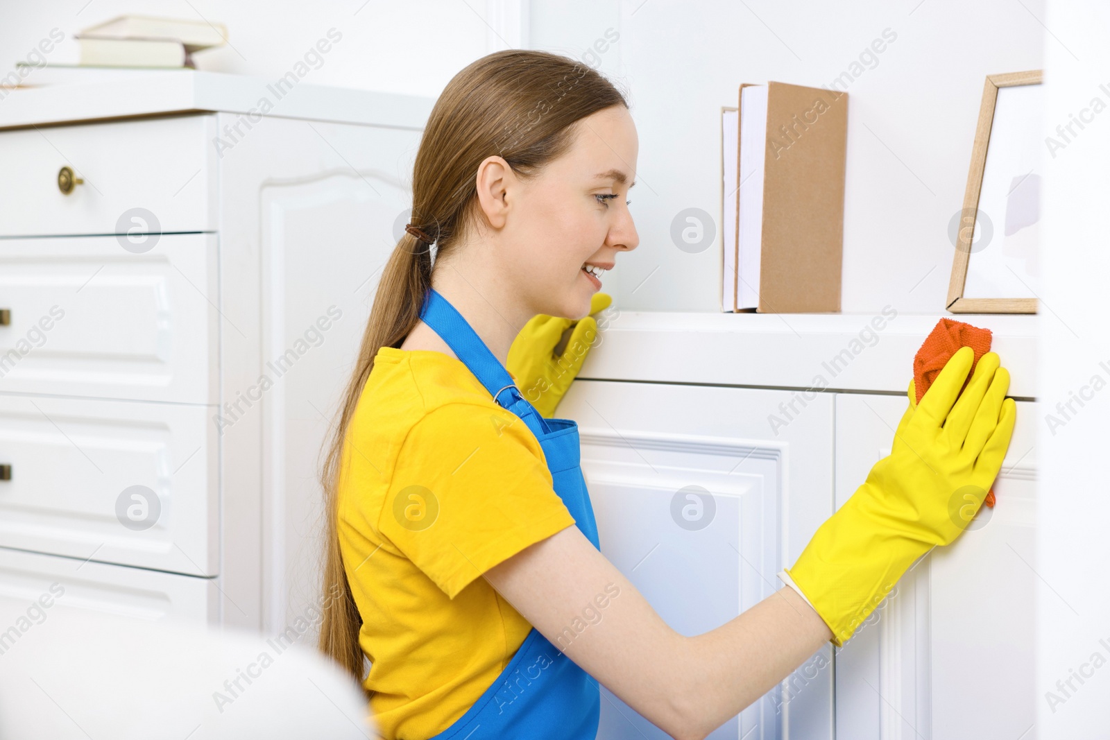 Photo of Woman cleaning furniture with rag at home