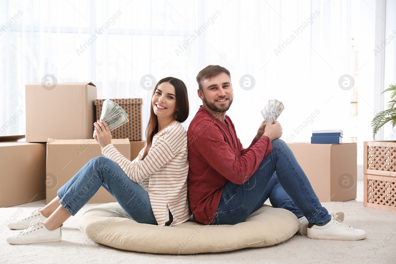 Photo of Beautiful young couple with money on floor at home