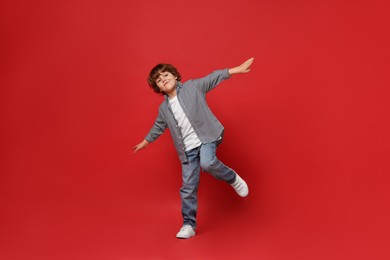 Photo of Happy little boy dancing on red background