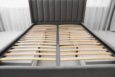 Modern bed with storage space for bedding under slatted base in room, closeup