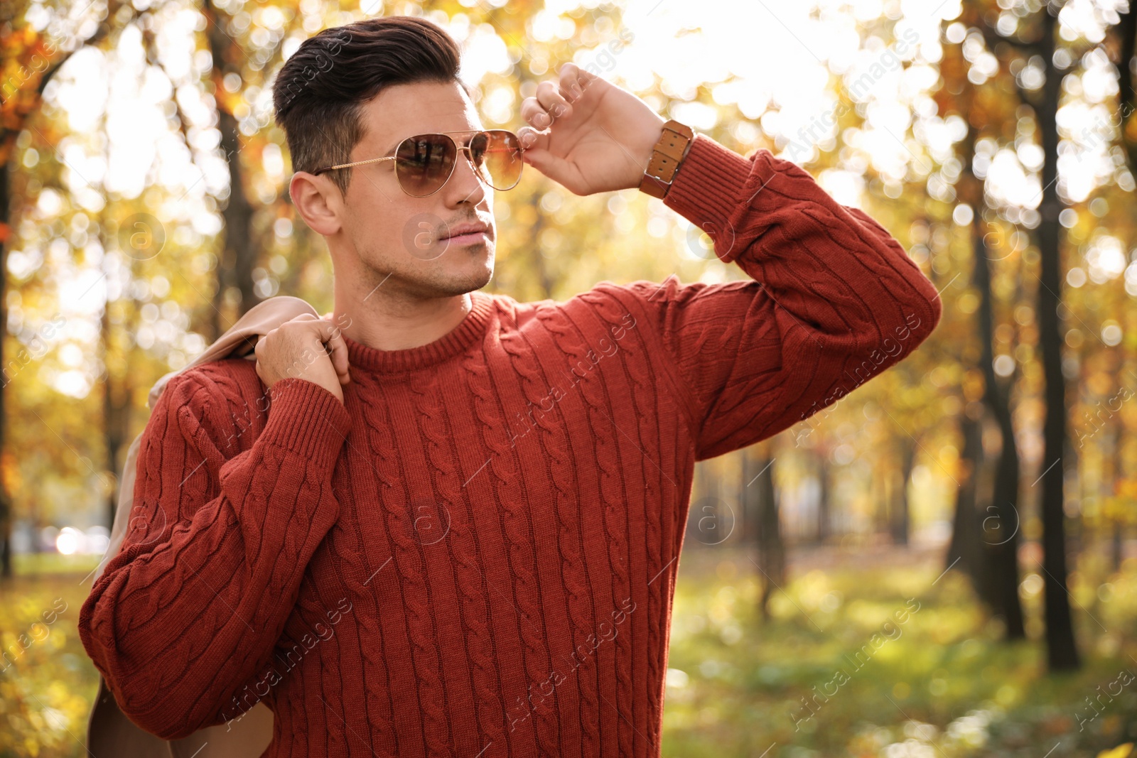 Photo of Handsome man walking in park on autumn day