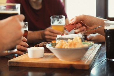 Photo of Friends drinking beer and eating snacks at table in pub