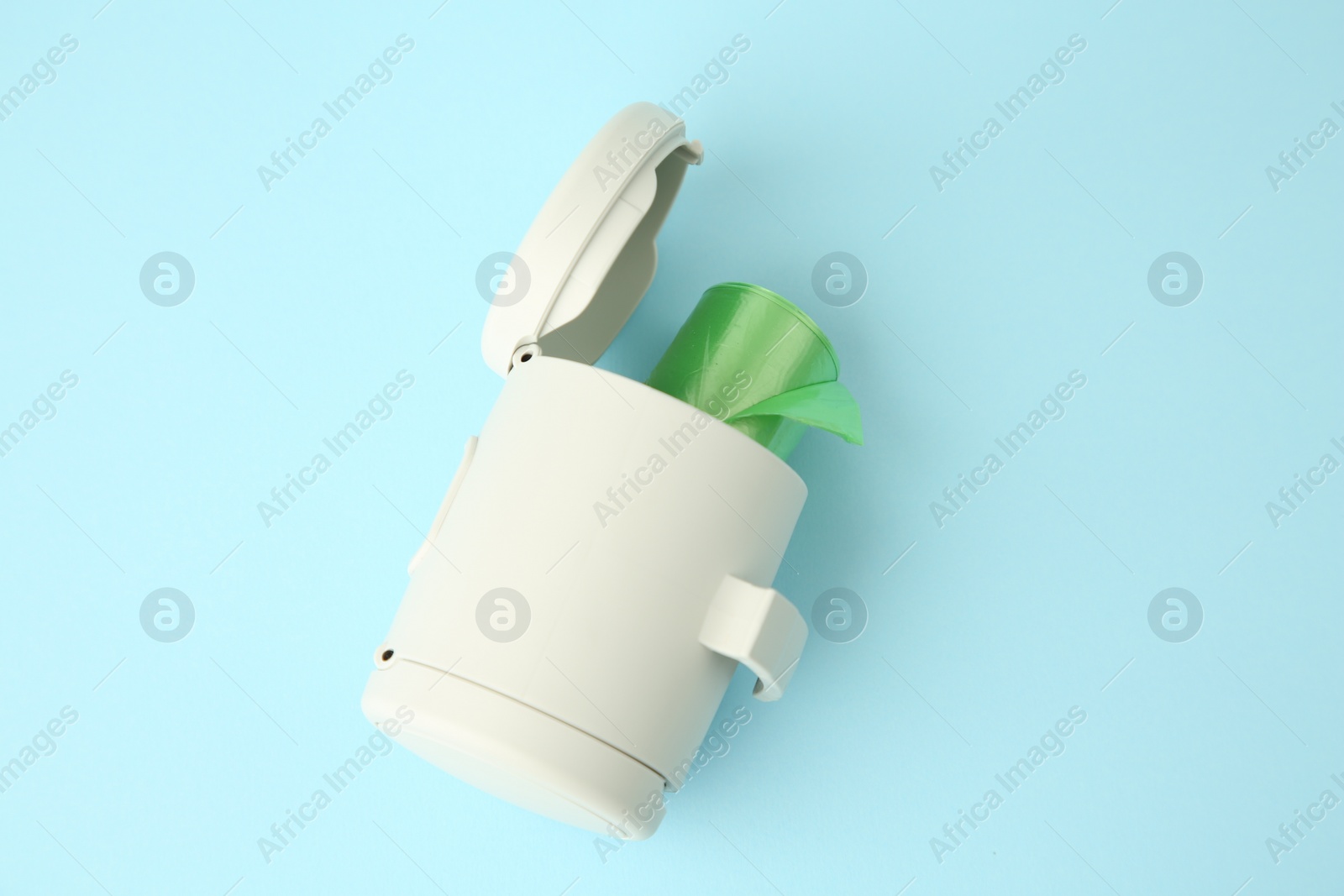 Photo of Dispenser with dog waste bags on light blue background, above view