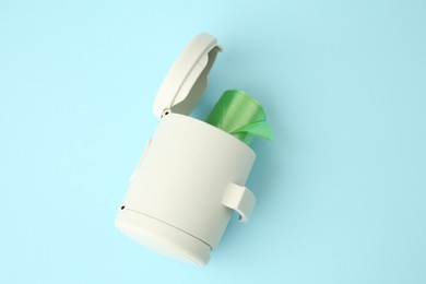 Dispenser with dog waste bags on light blue background, above view