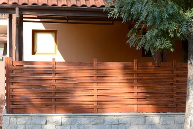 Photo of Wooden fence near house on sunny day outdoors